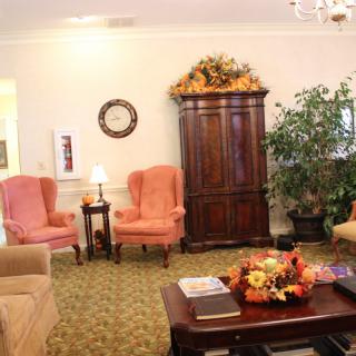 A cozy living room with armchairs, a coffee table decorated with autumn-themed ornaments, and a large cabinet.