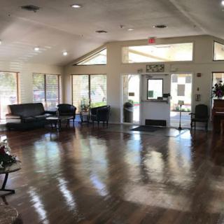 A spacious and well-lit interior waiting area with chairs, tables, and large windows.