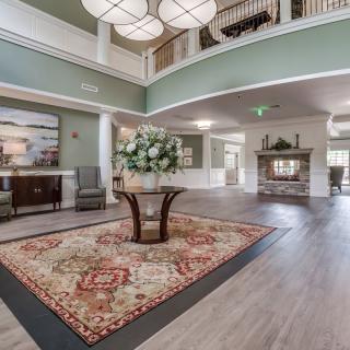 A spacious and elegantly designed lobby with a central floral arrangement on a decorative table and modern lighting fixtures.