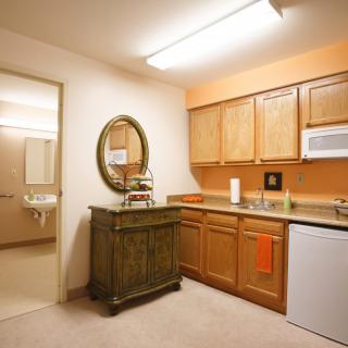 A small kitchenette with wooden cabinets, a microwave, and a mini fridge.