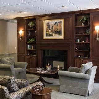 A cozy lounge area featuring a fireplace, armchairs, and bookshelves.