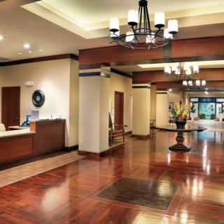 A spacious hotel lobby featuring elegant chandeliers and polished wooden floors.