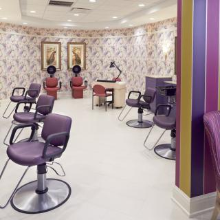 A modern hair salon interior with purple chairs and hair dryers.