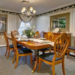 A well-appointed dining room with an elegant wooden table and chairs, a chandelier overhead, and tasteful decor including a mirror and wall art.