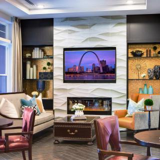 A stylish living room with elegant furniture and a television mounted above a decorative fireplace.