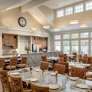 A bright and spacious dining room with set tables and a view of the kitchen area.