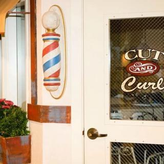 Entrance to a barbershop featuring a classic barber pole and signage on the door.