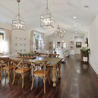 A spacious open-plan dining and living area with elegant wooden furniture and chandeliers.