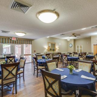 A well-arranged dining room with multiple tables and chairs, featuring a cozy interior design.