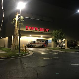 Emergency entrance of a hospital at night with an ambulance parked outside.