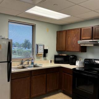 A modern kitchen with wooden cabinets, a stove, microwave, refrigerator, and a window providing natural light.