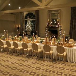 An elegantly set long dining table decorated for a festive holiday banquet with candles and greenery.