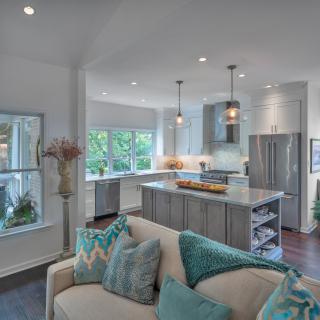 A modern open-concept kitchen and living area featuring an island counter, pendant lighting, and stainless steel appliances.
