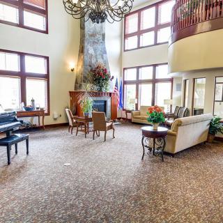 A spacious and elegantly designed living room with high ceilings, large windows, a central fireplace, and comfortable seating.