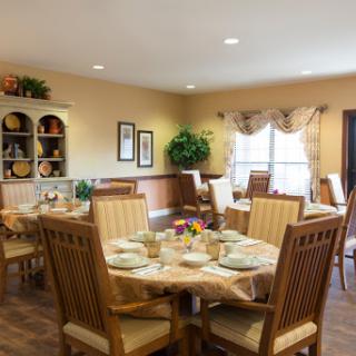 A cozy dining area with elegantly set tables, featuring warm colors and a welcoming atmosphere.