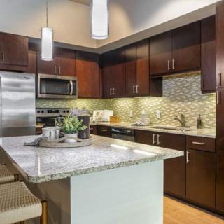 A modern kitchen featuring dark wood cabinets, granite countertops, and stainless steel appliances.
