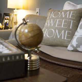 A cozy living room setting featuring a decorative globe and a pillow with 'Home Sweet Home' text.