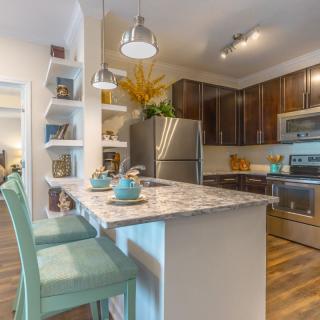 A modern kitchen with stylish countertops, stainless steel appliances, and decorative open shelves.