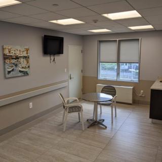 A modern hospital waiting area with chairs, a table, and a television.