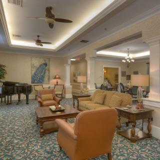 A cozy living room with comfortable seating, ceiling fans, and decorative artwork.