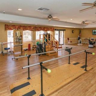 A well-equipped rehabilitation room featuring parallel bars and various exercise equipment for physical therapy.