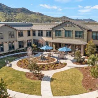 A modern building with a landscaped garden and mountain views.