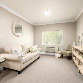 A cozy living room with beige tones, featuring a sofa, armchair, and decorative mirror.
