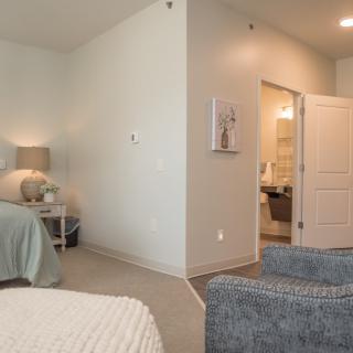 A cozy bedroom with a bed, nightstand, and an open door leading to another room.