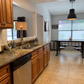 A bright kitchen with wooden cabinets, granite countertops, and a dining area featuring a pendant light.