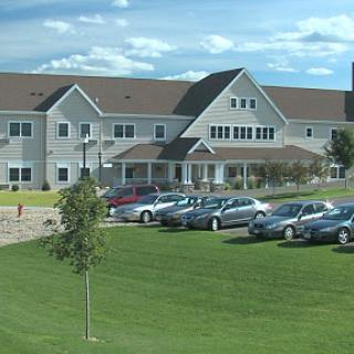 A residential building with a well-maintained parking lot and green lawn under a blue sky.