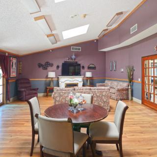 A spacious living room with modern furniture, featuring a seating area around a fireplace and a round table with chairs.