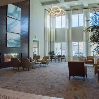 A spacious and modern lobby with ample seating, large windows, and a decorative chandelier.