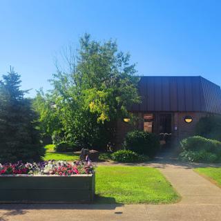 A serene outdoor view featuring a building surrounded by lush greenery and blooming flowers.
