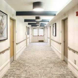 A modern, well-lit hallway with multiple doors and artwork on the walls.