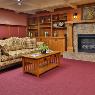 A cozy living room with a patterned sofa, wooden coffee table, and a fireplace surrounded by bookshelves.