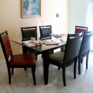 A dining room featuring a glass-top table surrounded by six chairs.