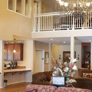 A cozy living room with a chandelier and an upper balcony.