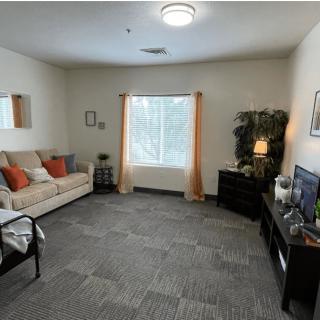 A cozy living room with a sofa, television, and large window with curtains.