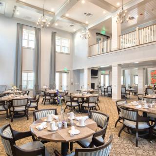 An elegant dining area with neatly arranged tables and chairs under a high ceiling.