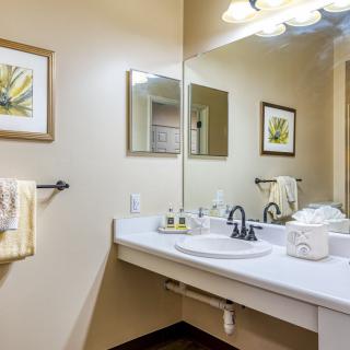 A neatly arranged bathroom with a large mirror, sink, and decorative artwork on the walls.