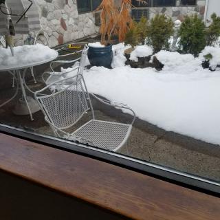 A snowy patio with outdoor furniture covered in snow.