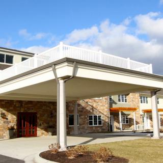 A modern building entrance with a covered canopy set against a blue sky.