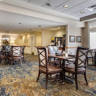 A cozy dining area with multiple tables and chairs, featuring a carpeted floor and elegant decor.