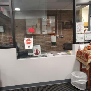 A view of an office service window with informational signs.