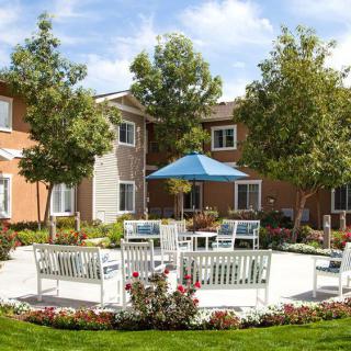 A serene courtyard with patio furniture and lush greenery in an apartment complex.