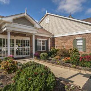 A charming residential building with a landscaped entrance and brick exterior.