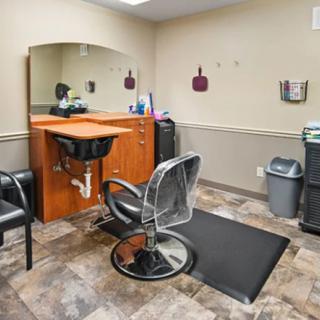 A well-equipped hair salon station featuring a styling chair, mirror, and storage cabinets.