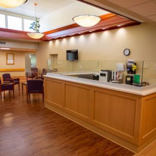 A welcoming reception area in a medical facility, featuring a wooden counter and comfortable seating.