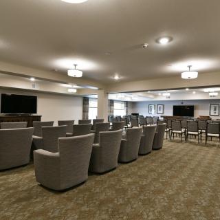 An arranged seating area in a conference room with multiple chairs and televisions.