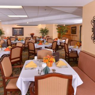 A well-decorated dining room with multiple tables set for a meal, featuring elegant table settings and comfortable seating.